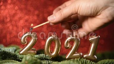 假日背景2021年新年快乐。 2021年的数字是由在红色的节日闪闪发光的背景上燃烧金蜡烛制成的。